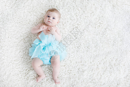 白色背景的可爱女婴穿着绿松石短裙可爱的小孩笑着快乐无忧虑的宝贝童年图片