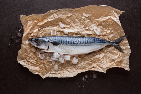 黑背景的手工艺纸上的冰上新鲜竹鱼海产食品餐厅有机烹饪材料顶视图片