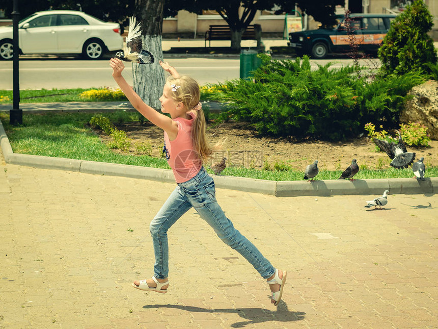 女孩在夏天抓一只飞鸽子孩子在镇广场上图片