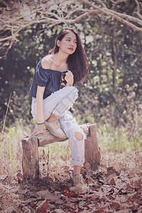 年轻的亚洲时尚模特女模特在干叶林中拍图片
