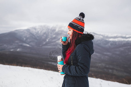 女在冬季山中漫步时拥有热饮图片