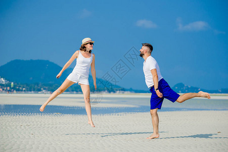 快乐的年轻情侣在沙漠阳光明媚的沙图片