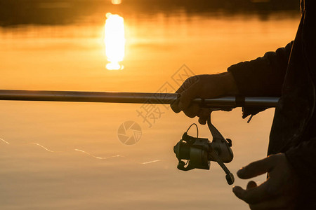 日落时有人在船上钓鱼图片