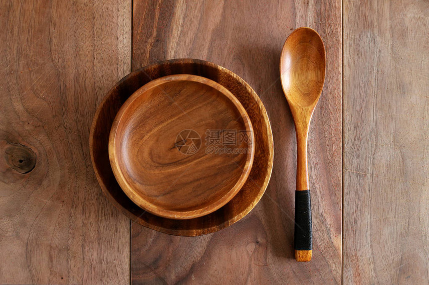 在一个木板餐桌上摆放着一个空的看得见的木质谷物碗图片