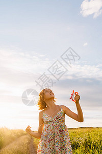 穿着裙子的女孩拿着明亮的风筝在绿色夏日田里图片