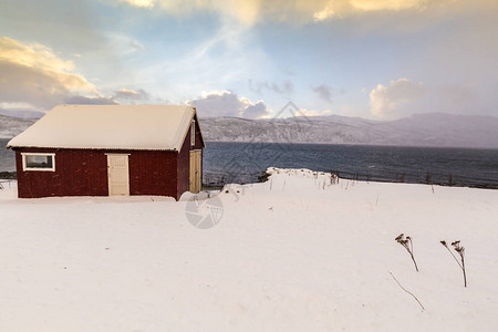 典型的挪威温暖舒适的房子位于挪威特罗姆斯县峡湾的湖边图片