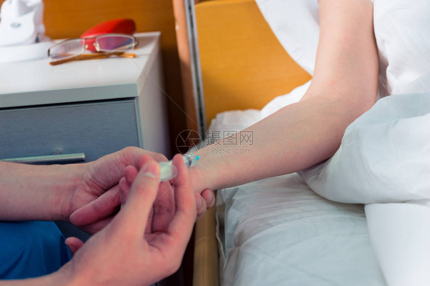 穿制服的医生正在给躺在病房床上的病人打针图片