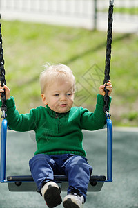 一岁大的婴儿男孩在游乐场秋天穿着绿色毛衣绿毛衣图片