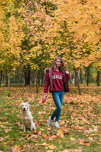 秋天公园的年轻女子和她的狗一起散步友谊图片
