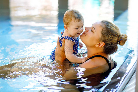 快乐的妈和可爱的小女儿在游泳池里游泳图片