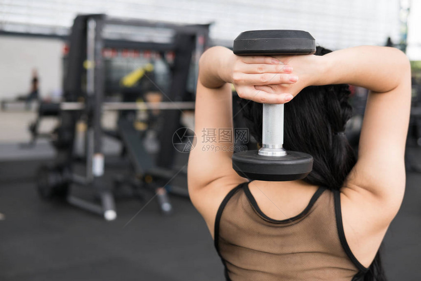 年轻女子在健身中心执行锻炼女运动员在健身房举哑铃运动型亚洲女孩在健图片
