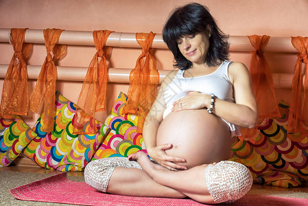 40周怀孕的40周中年成幼女坐在Asana做瑜伽练习图片