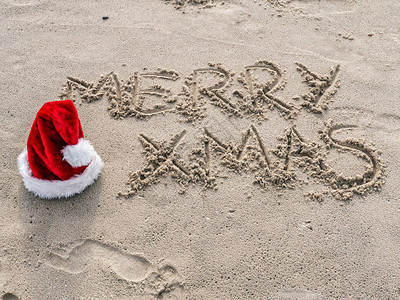 圣诞快乐问候在沙滩上手工写作用红图片