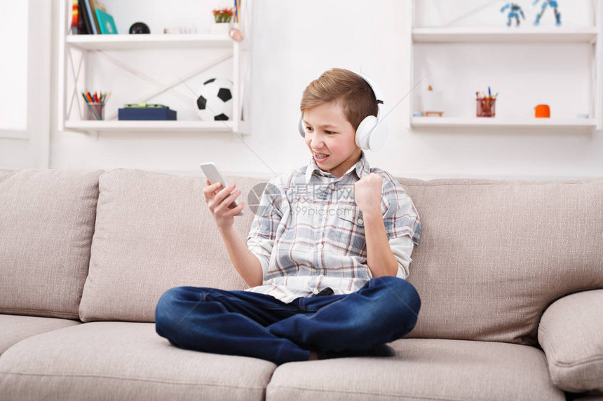兴奋的十几岁男孩带着牙套在智能手机上玩足球比赛图片
