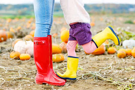 年轻女子和她的小女孩儿穿着雨靴的腿图片