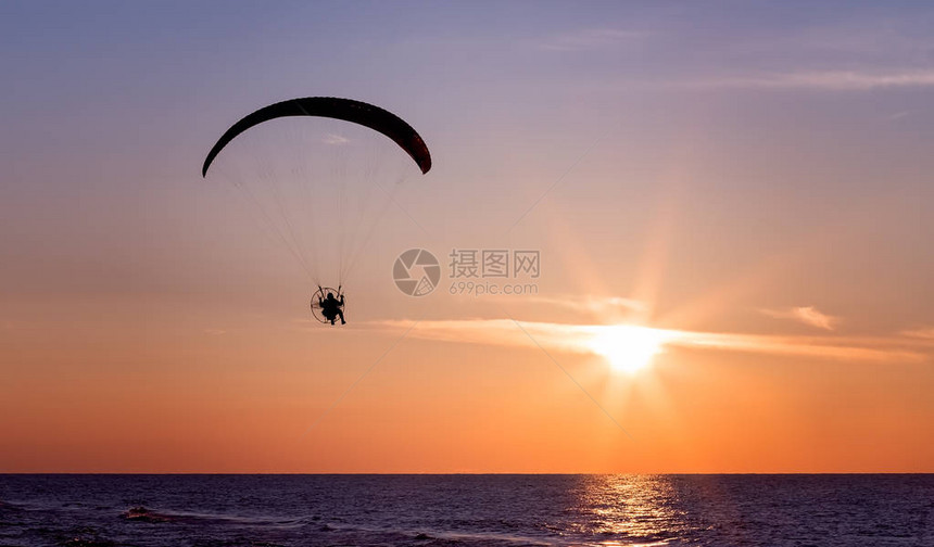 在美丽的日落中滑翔伞与半摩图片