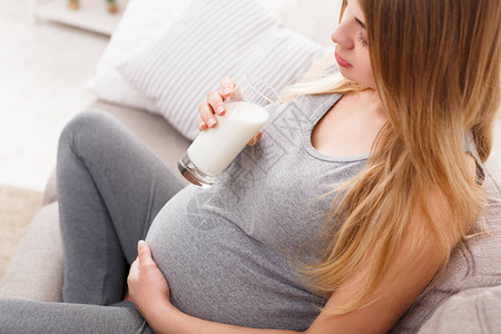 孕妇喝杯牛奶特写年轻的期待金发女郎享受健康的饮料医疗保健营养维生图片