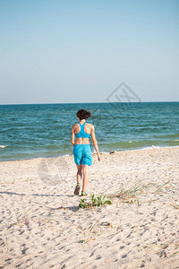 这女孩沿着海边的沙子跑去准备马拉松赛事假期间好背景