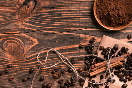 乡村木桌上的咖啡豆肉桂棒和磨碎的咖啡图片