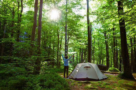 女孩站在帐篷附近醒来后在森林里图片