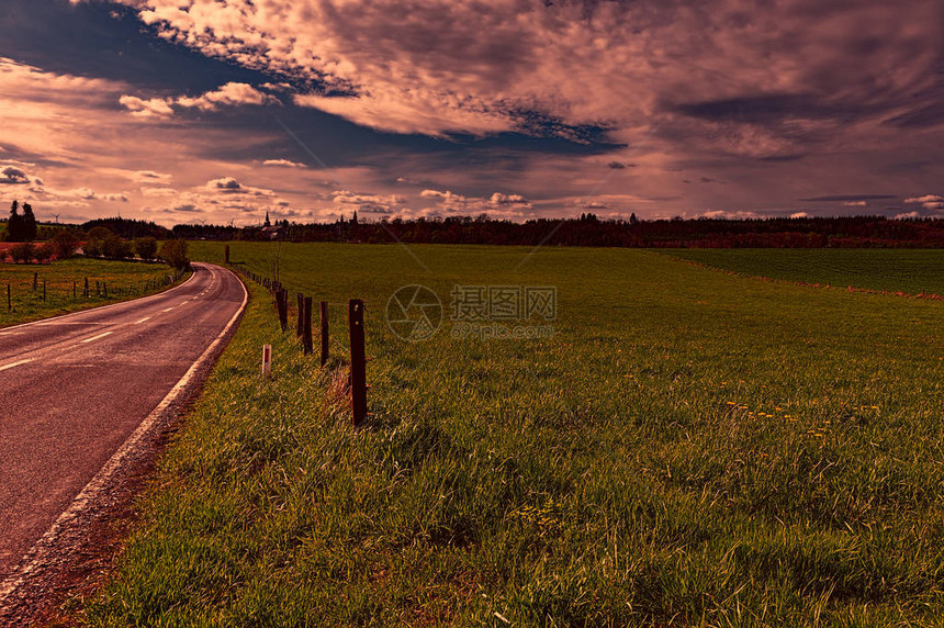 比利时日落时分春田与绿草之间的乡间小路与草甸和牧场地图片