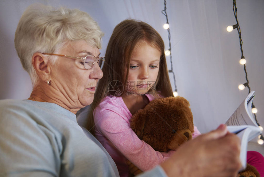外祖母和孙女在睡觉前读故事书我们的图片