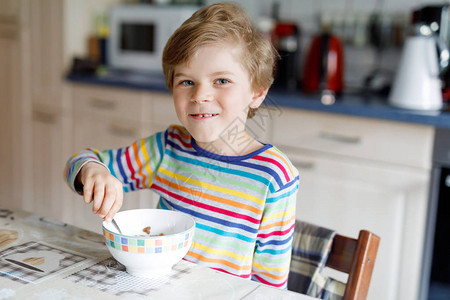 可爱的快乐金发小男孩早餐或午餐吃自制麦片儿童健康饮食在托儿所学图片