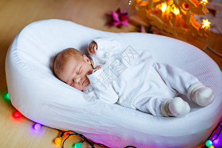 一周大的新生婴儿睡在圣诞树旁背景图片