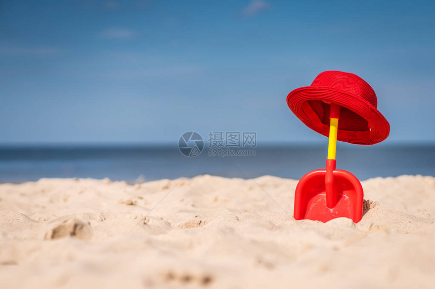 红色和黄色塑料儿童玩具铲子和在美丽的白沙海图片