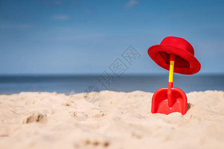 红色和黄色塑料儿童玩具铲子和在美丽的白沙海图片