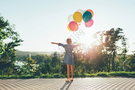 可爱的女孩抱着五颜六色的气球在市公园明末清初ar背景图片