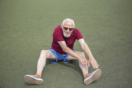 这位老人正在露天的体育场内练习健康生活方式的概念和为每个人提供的运动训练公共场所背景图片