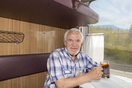 一位有魅力的老人在火车厢里喝茶图片