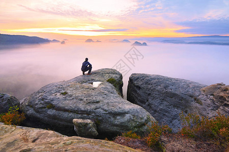 岩石峰顶上锋利的后方男子剪影满足徒步旅行者欣赏岩石峭壁的高个子观看下来风景生动而强背景图片