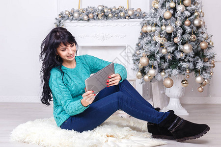 可爱的caucasian女人长褐发坐在室内在圣诞节装饰使用图片