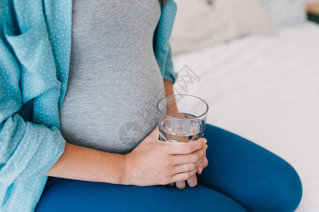 年轻怀孕妇女在家里用水杯抽图片