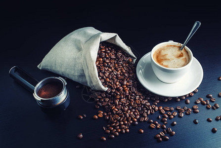 一杯咖啡烤咖啡豆帆布袋和黑厨房桌上一台咖图片