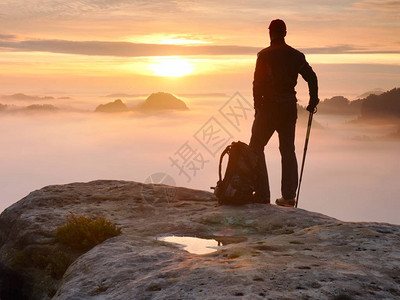 疲惫的徒步旅行者背着运动背包在岩石山峰上图片