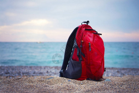红色旅行背包的红背包从架子右侧起立图片