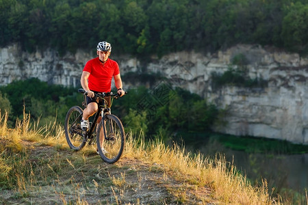 山地自行车员男子骑户外旅行者在秋季骑自行车反对日落骑自行车的人戴头盔图片