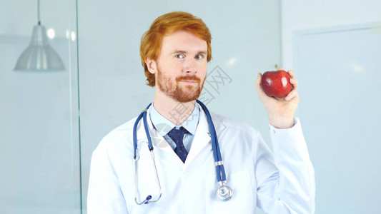 拿着红苹果看着相机的医生肖像图片