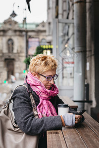 成年金发女郎坐在街上咖啡馆外的咖啡图片