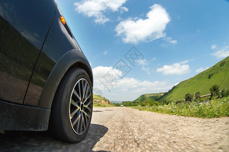 汽车侧面的特写镜头和一个在绿树和云彩的路边景观背景下高速沿着沥图片