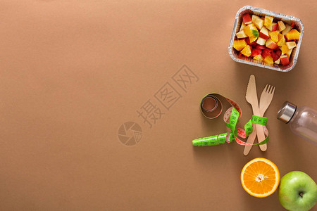 健康饮食和减肥背景复制空间卷尺包裹在刀叉和水果沙拉的顶视图上饮图片