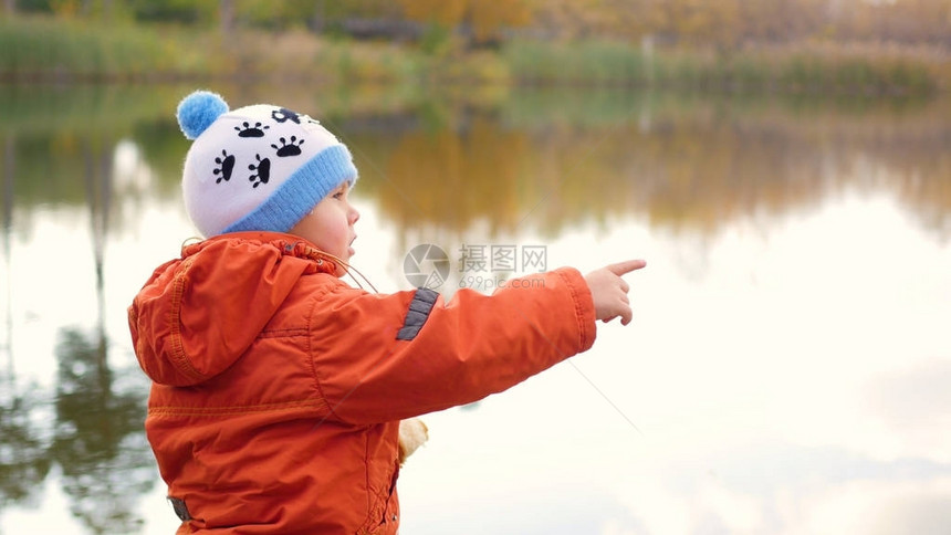 一个孩子站在池塘边扔石头图片