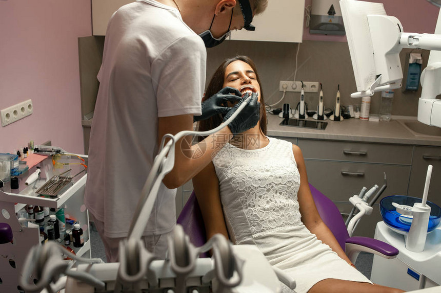 男牙医在牙科办公室用牙科钻头治疗图片