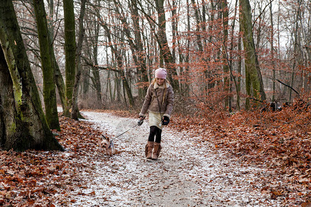 美丽的小女孩穿着羊皮大衣和靴子在秋冬和图片