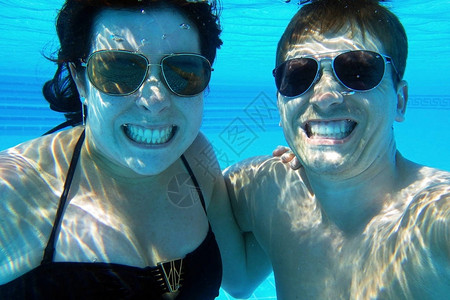 一对欢笑情侣的水下照片游泳池里一个笑的女人和图片
