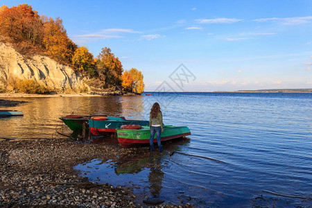 女孩站在停泊在石岸边的小船上图片