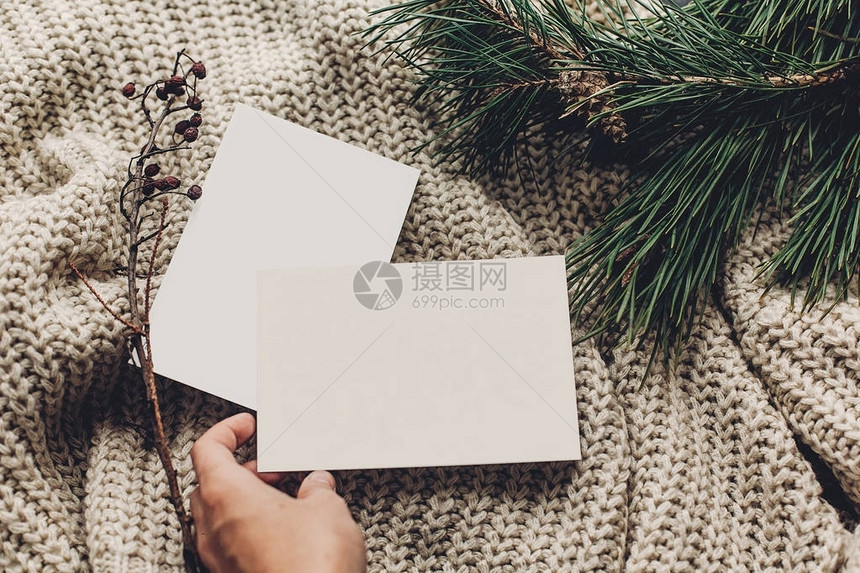 手拿着时尚针织毛衣背景上的空圣诞贺卡图片